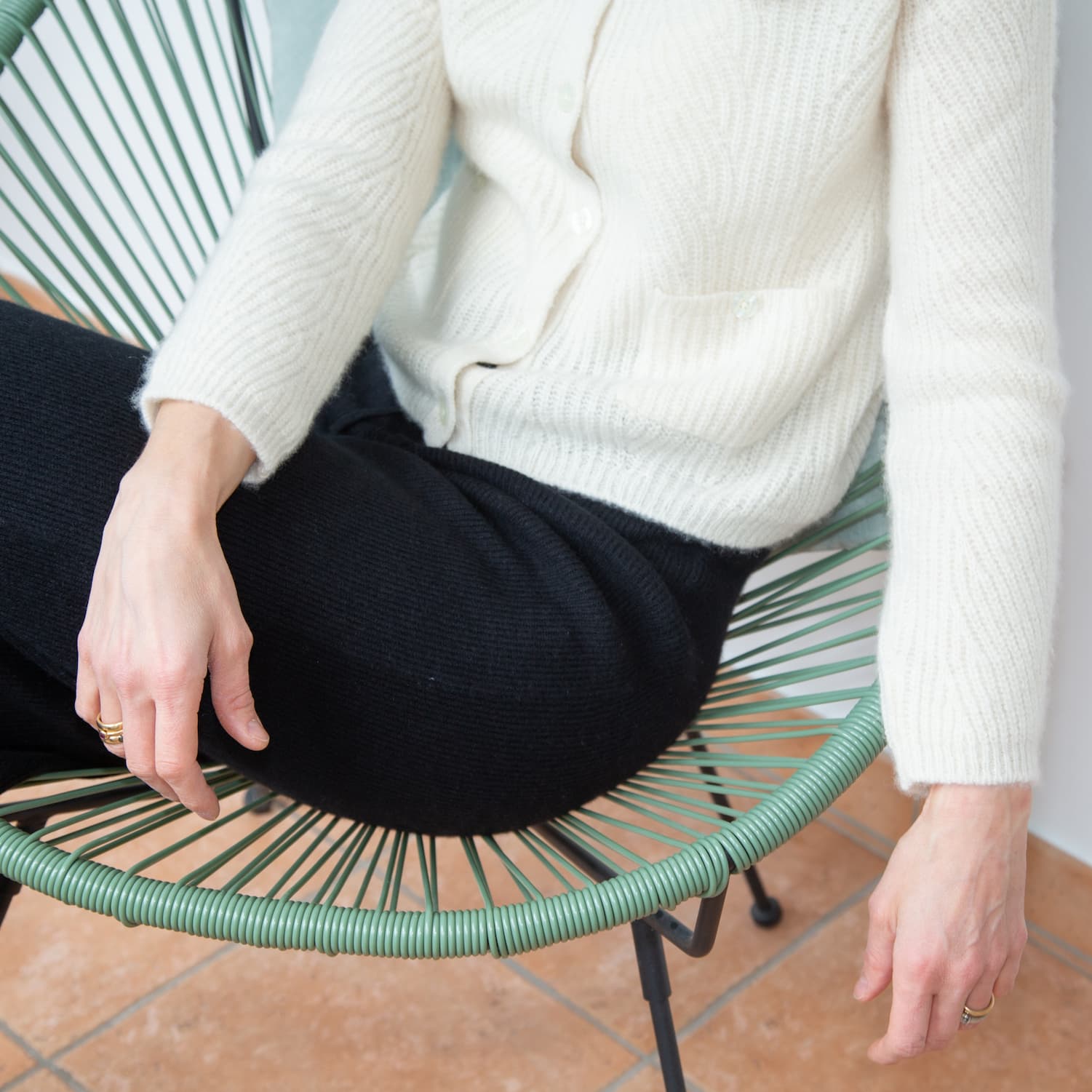 Ausschnitt Dame sitzend mit Kaschmirhose und -jacken in Schwarz und Naturweiss