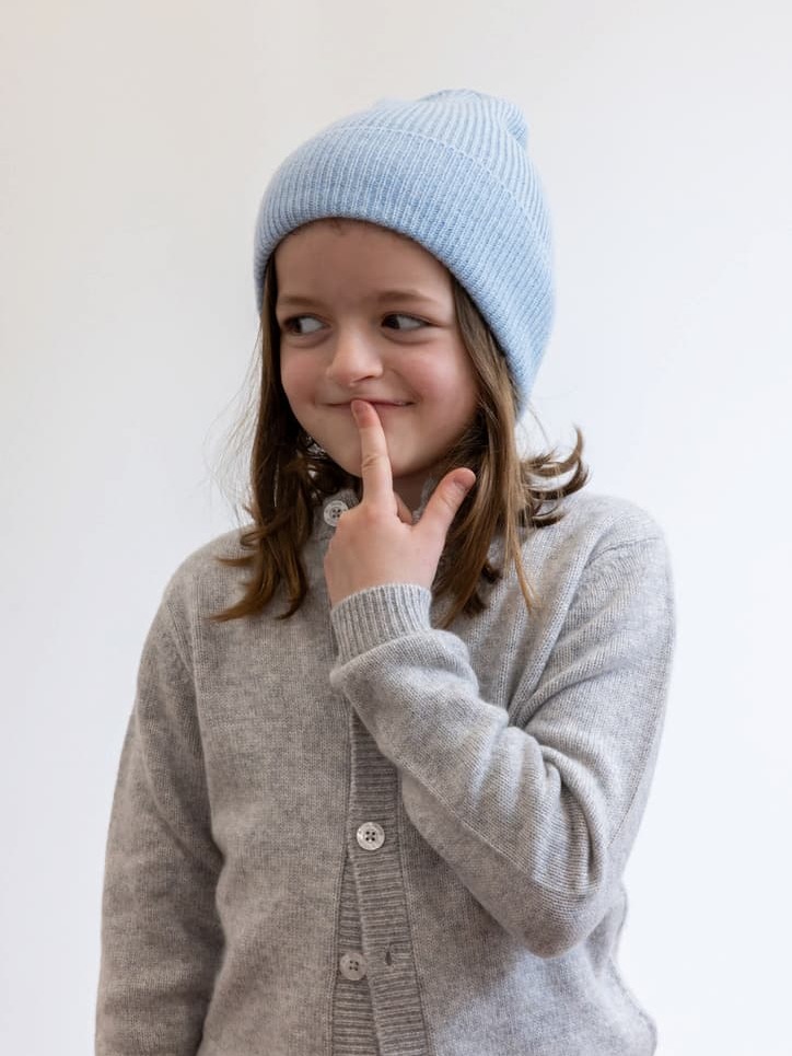 Mädchen mit blauer Kaschmirmütze und grauem Cardigan