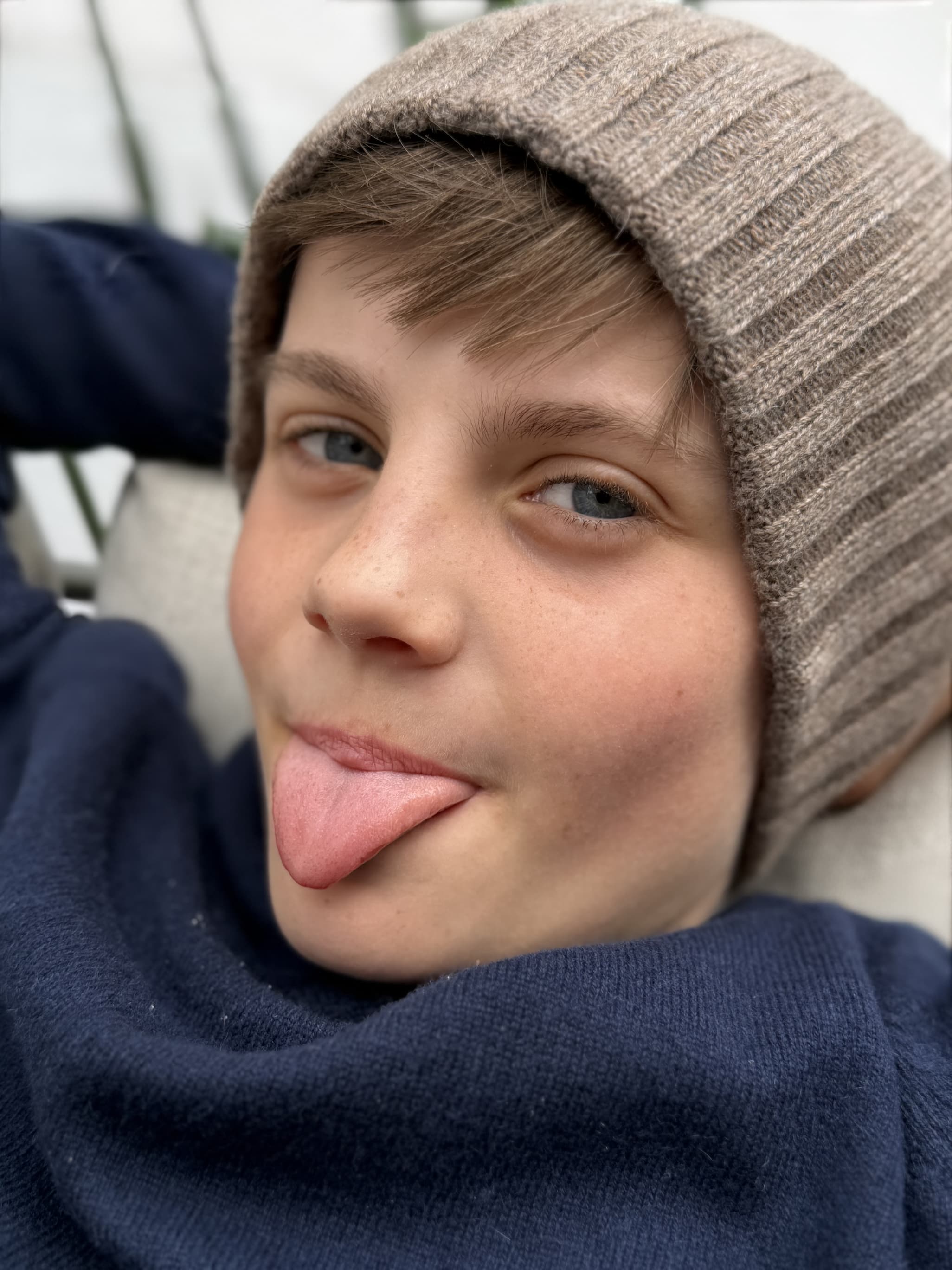 Portrait Kopf, Junge mit ausgestreckter Zunge und Mütze MATTI x