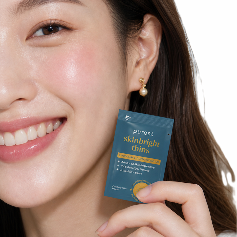 Woman smiling, holding up a SkinBright Thins strip