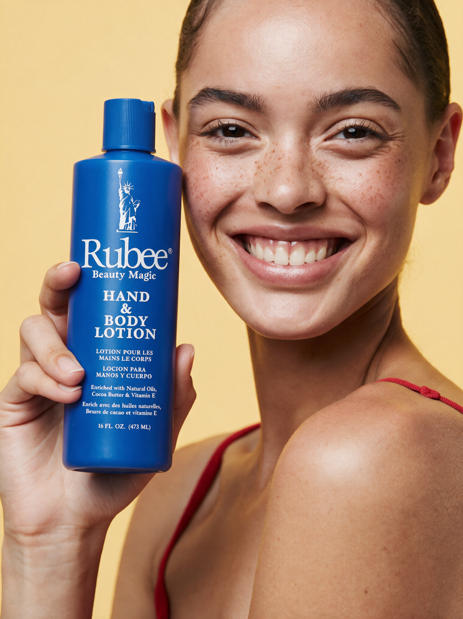 Smiling woman holding a Rubee Beauty Magic hand and body lotion bottle