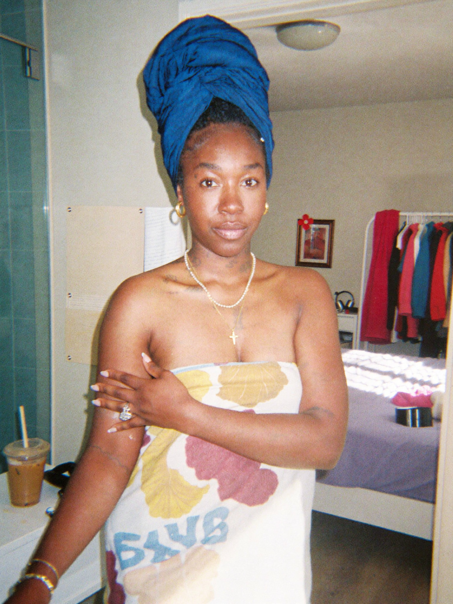 Woman wearing a blue hair towel and a patterned bath towel while getting ready
