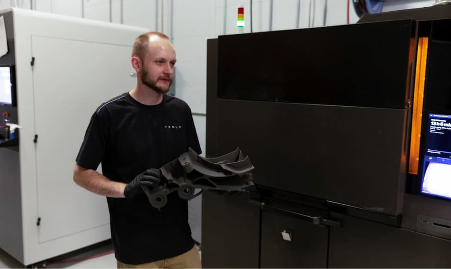 Tesla employee holding 3D-printed part