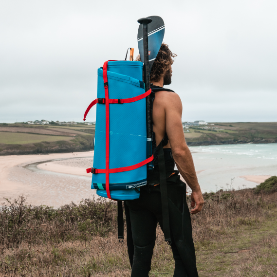Man carrying his Red Paddle Board on the beach