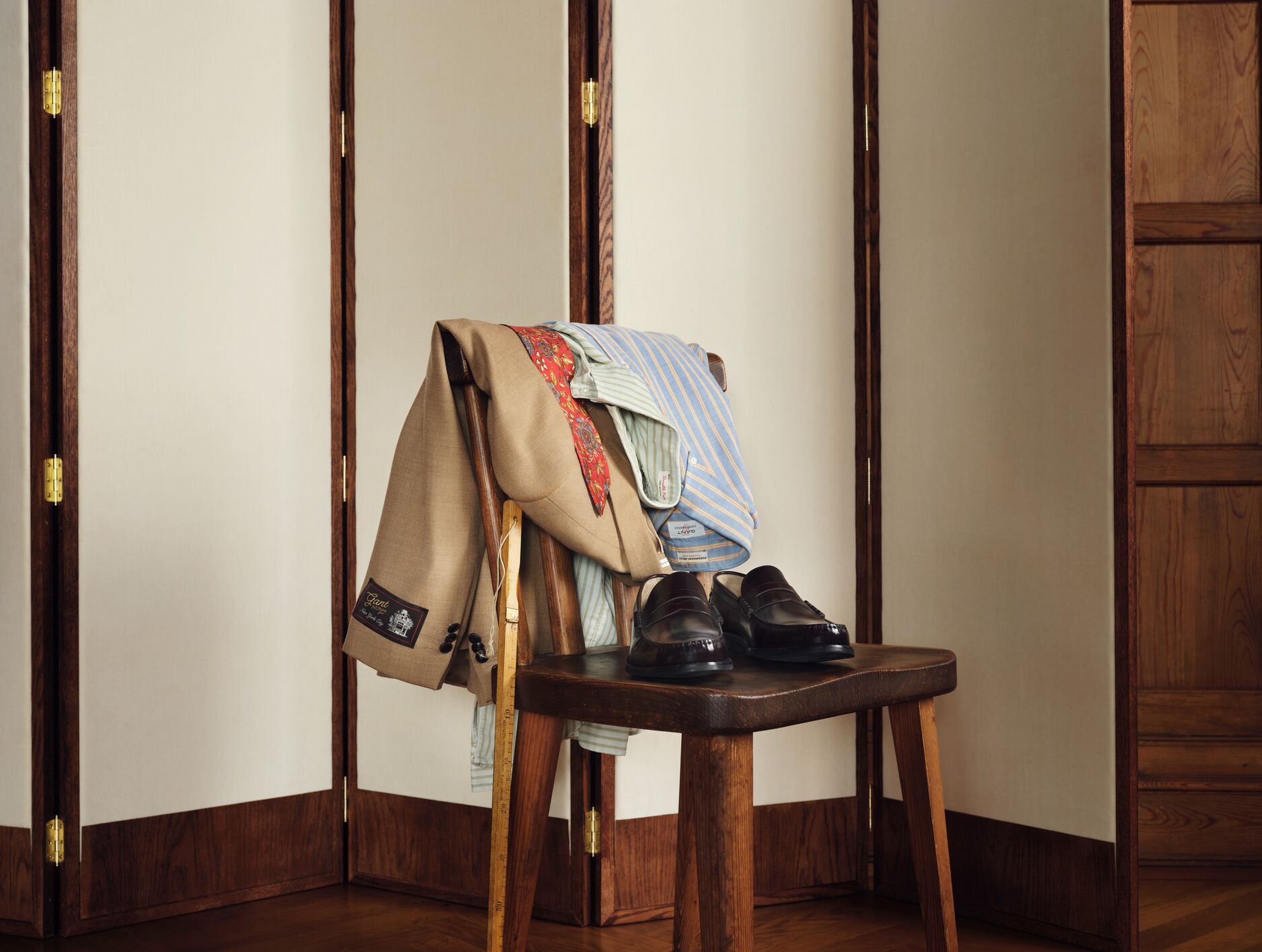 Bilde av et skrivebord med inspirerende magasiner og en stol med en blazer og slips pent hengende over. 