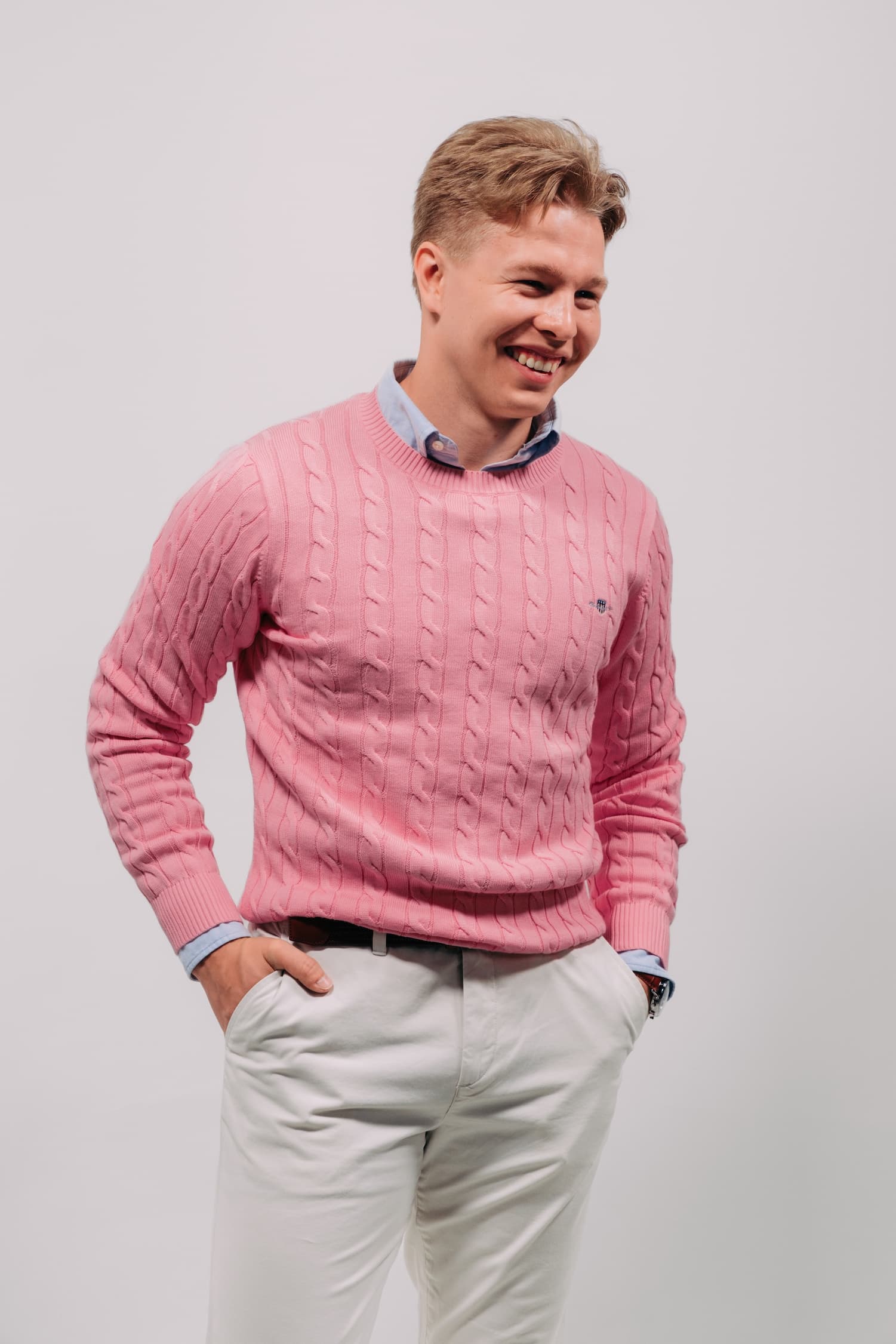 Markus Rooth in a pink cabel crewneck and white chinos posing