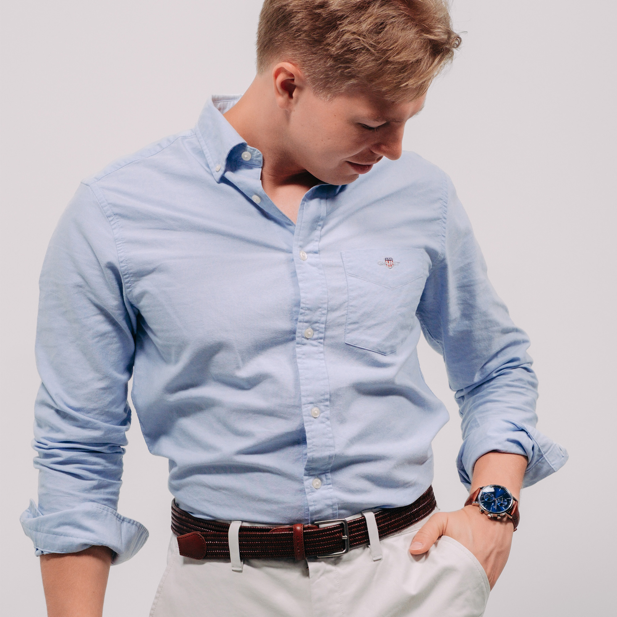 Markus rooth wearing a oxford shirt casualy looking down on his watch