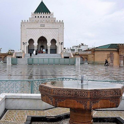 White temple with a courtyard and fountain in the foreground 