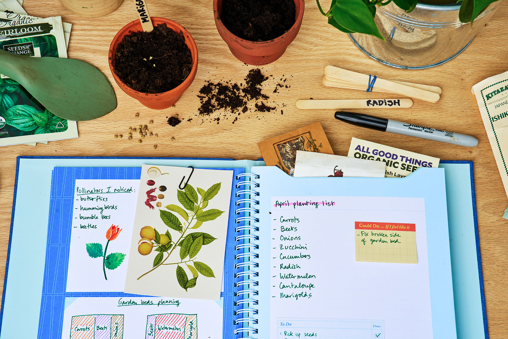 The Memento Journal lies open on a table among pens and gardening supplies