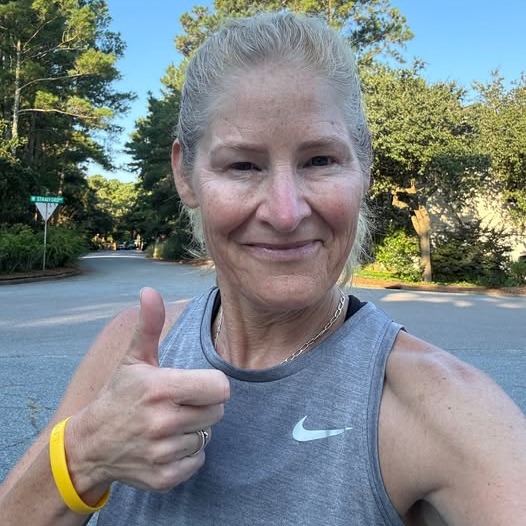 A woman in athleticwear giving a thumbs up