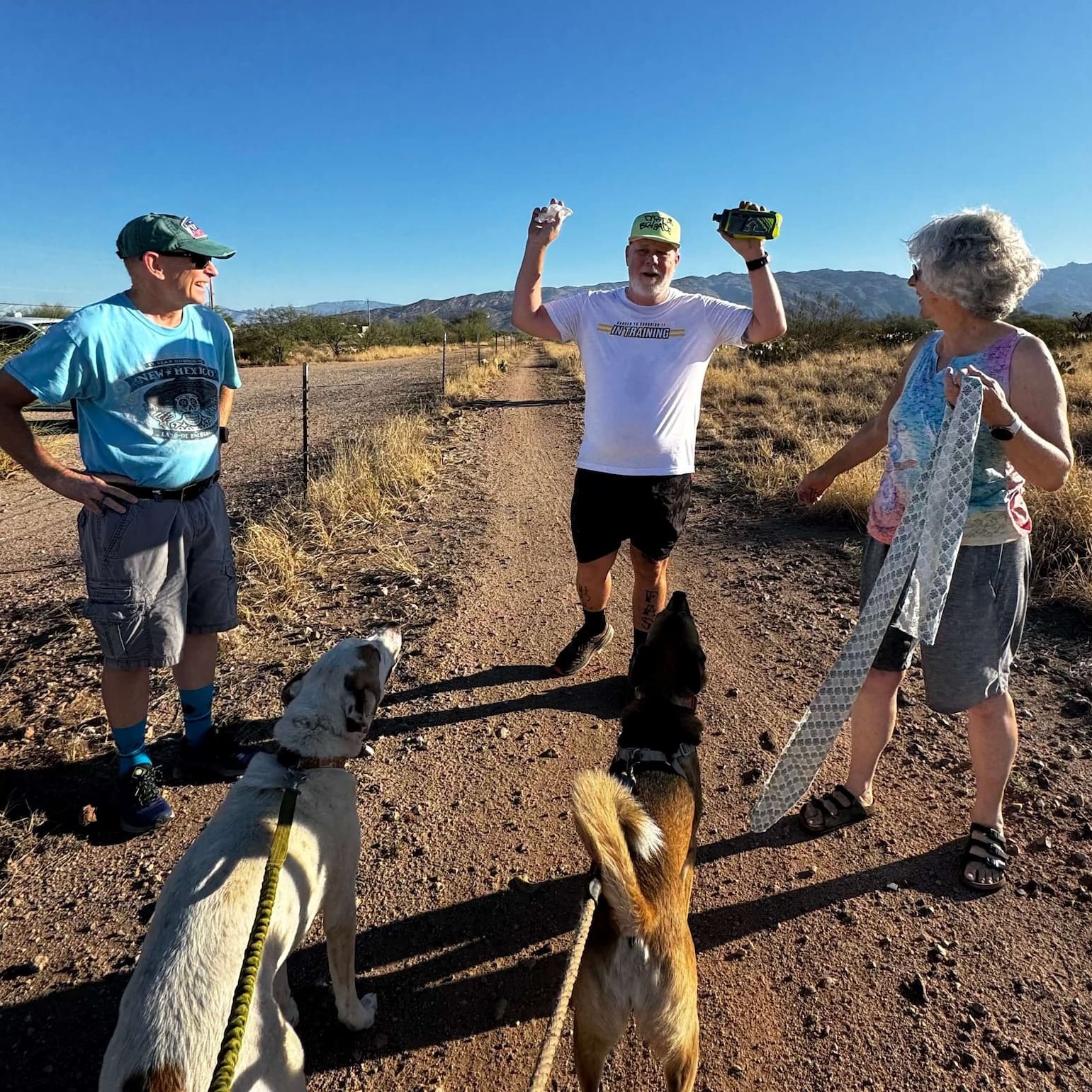 3 people and 2 dogs walking on a trail