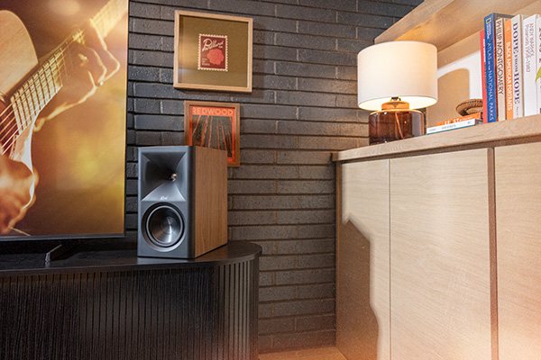 The Fives II sitting on a black side-table next to a large flat-screen TV. The Scene is set in a warmly-lit living room.