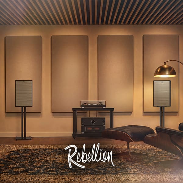 Curated living room with a pair of Klipsch Rebellion speakers situated on speaker stands, the the word Rebellion over the image