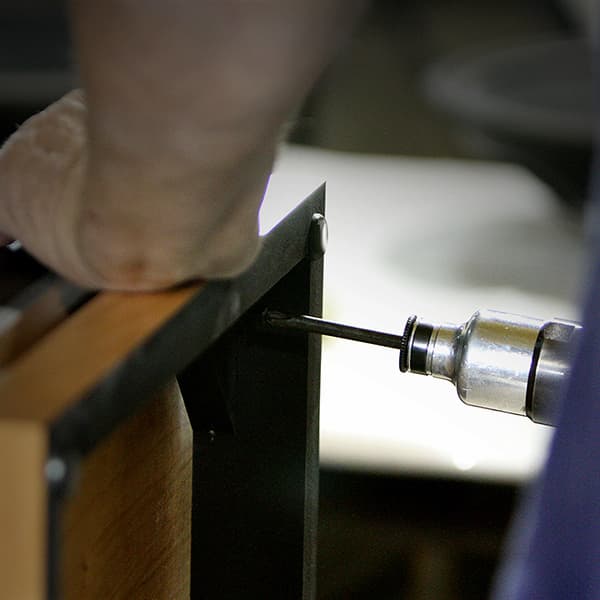 Close-up of a man hand crafting a wooden speaker with a drilling tool