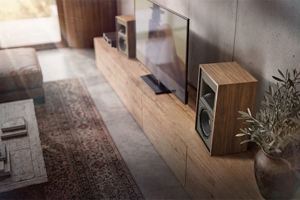 Curated living room with a pair of Klipsch Rebellion speakers sitting on top of a wooden cabinet.