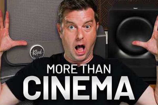 Man named Caleb, has his arms raised in surprise, with Klipsch Flexus products behind him. Claiming it's more than cinema.