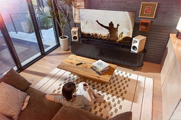Young woman watching tv in a stylish living room, with a pair of Red Oak, Klipsch Fives II's monitor speakers