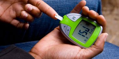 Hands holding a glucose meter with a strip inserted