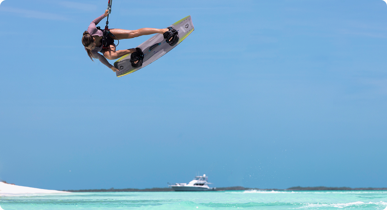 Kitesurfer jumping with a Duotone Soleil twintip against a clear blue sky