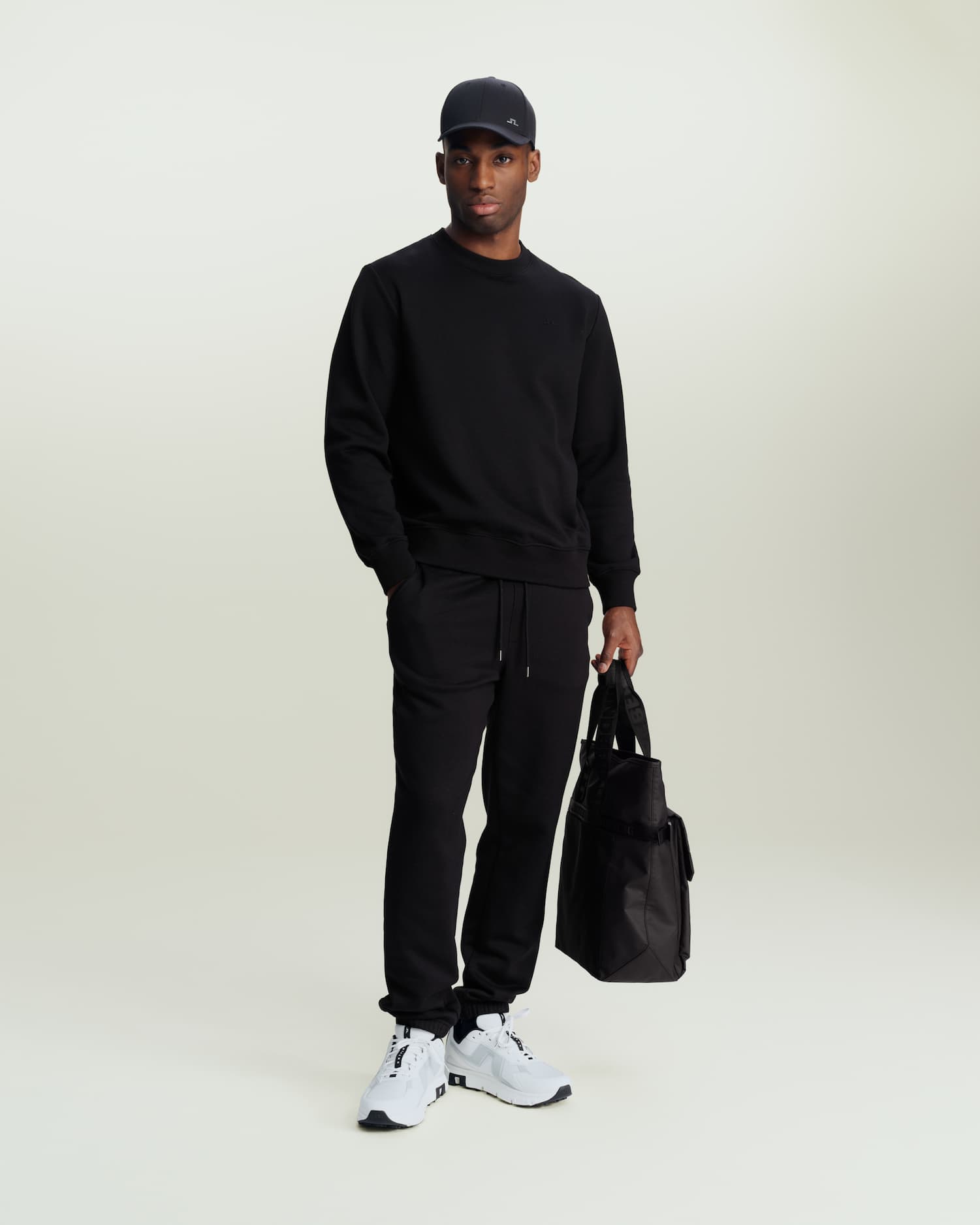 an image of a man in a black sweatshirt and sweatpants holding a bag