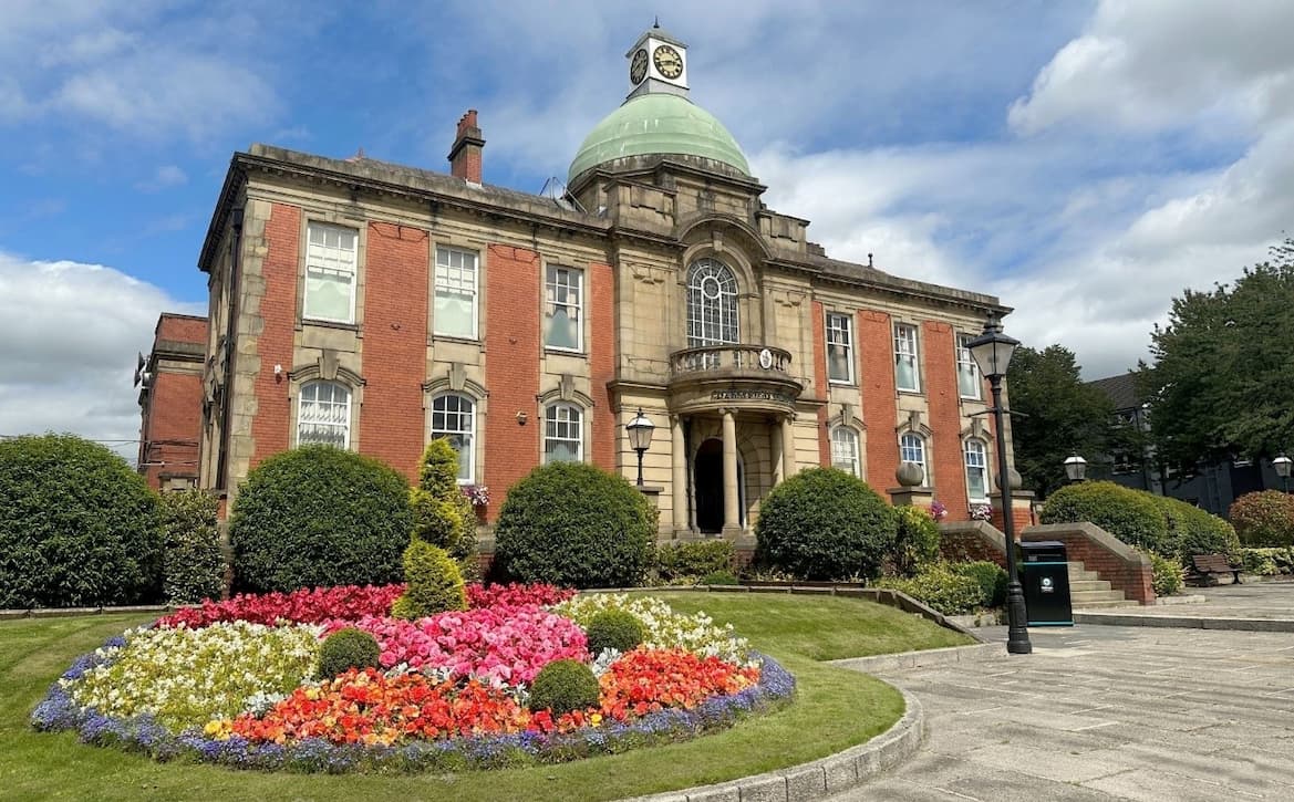 The historic Chadderton Town Hall with beautiful floral gardens bathed in sunlight 