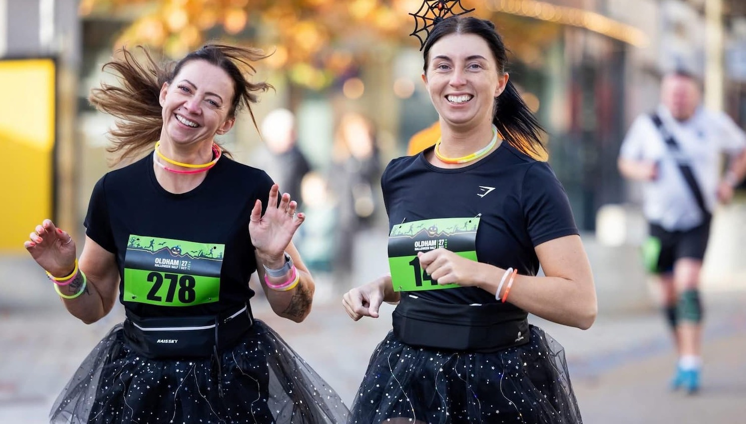 Two women running side by side wearing black outfits at last year's Halloween Half 