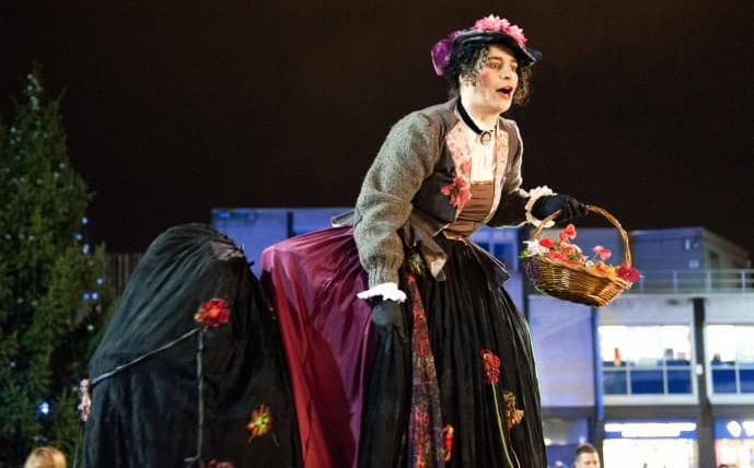 A stiltwalking Victorian belle in shimmering scarlet 