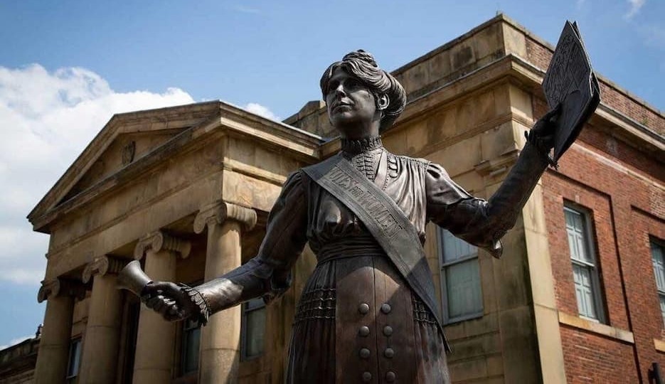 A statue depicting suffragette Annie Kenney, wearing a votes for women sash and ringing a bell, in Parliament Square