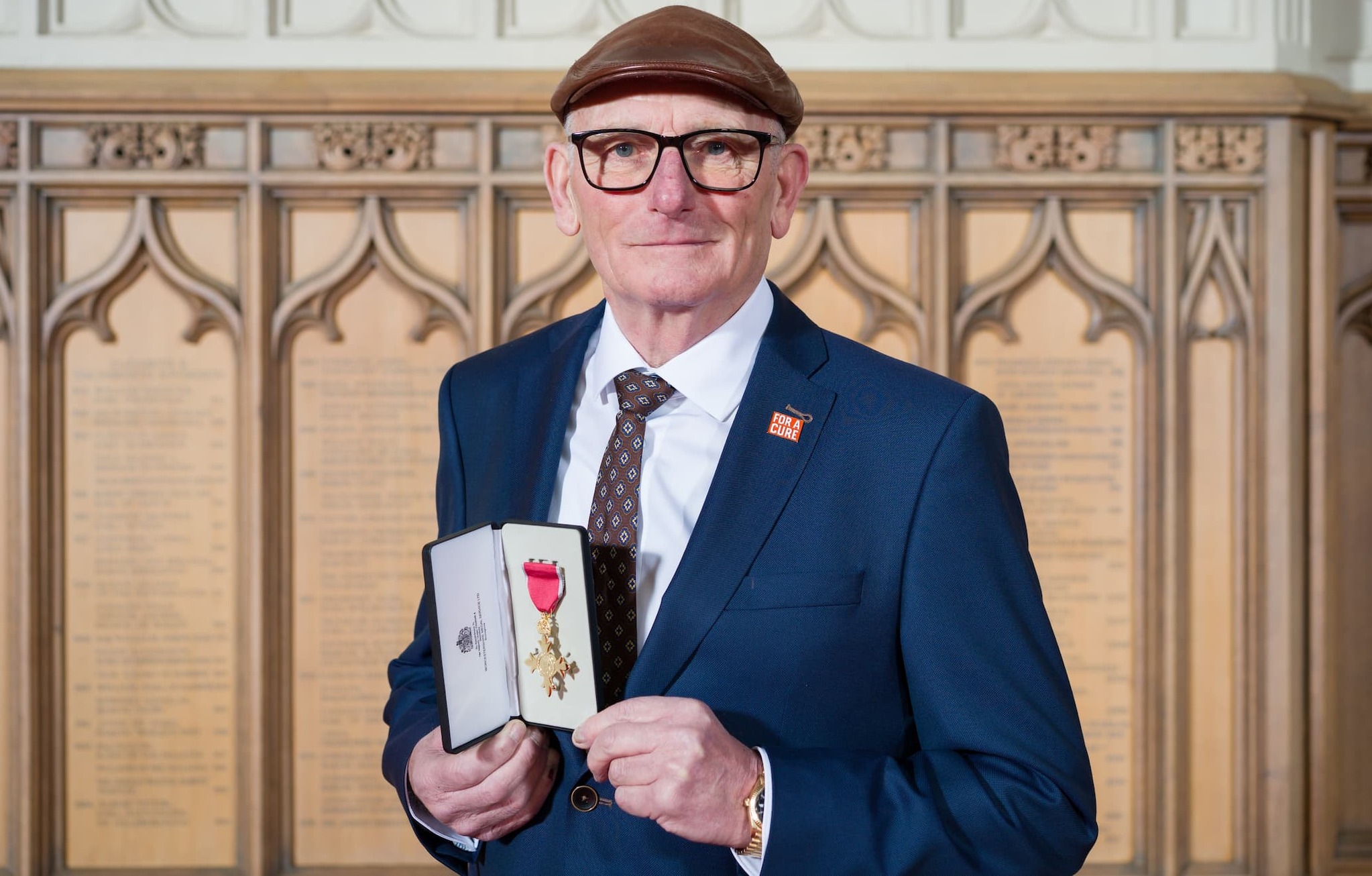Frank Rothwell holding his OBE at Windsor Castle wearing his signature flat cap