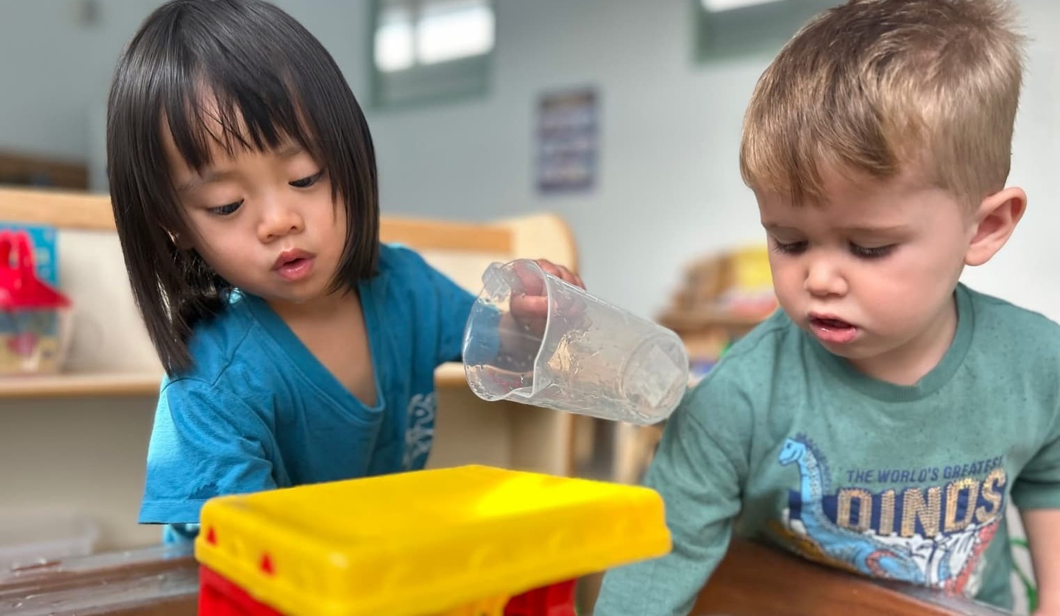Two young children playing with water and toys at Alexandra Family Hub