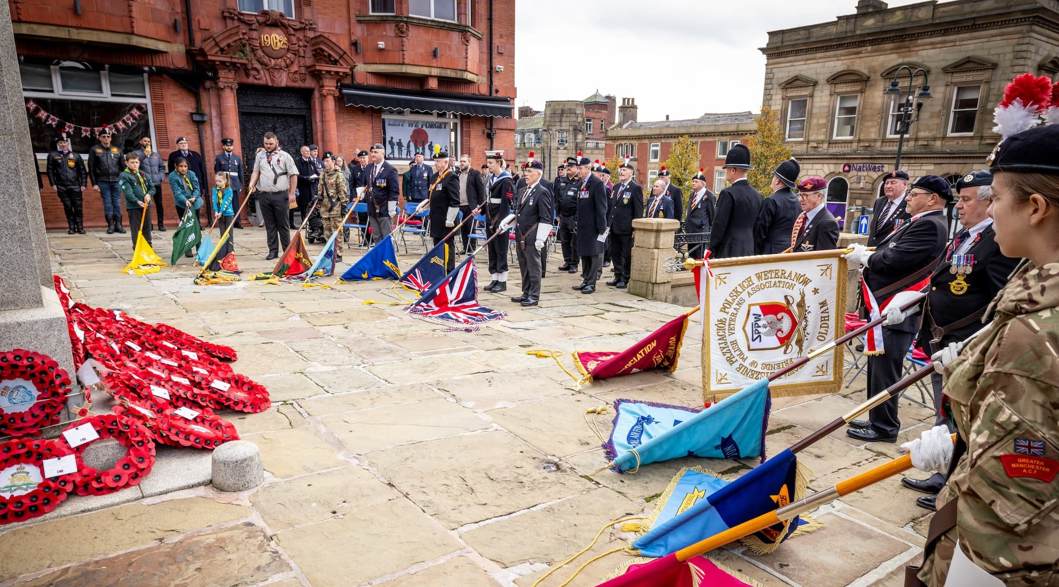 Veterans and uniformed services standing together at the War Memorial opposite the Old Town Hall