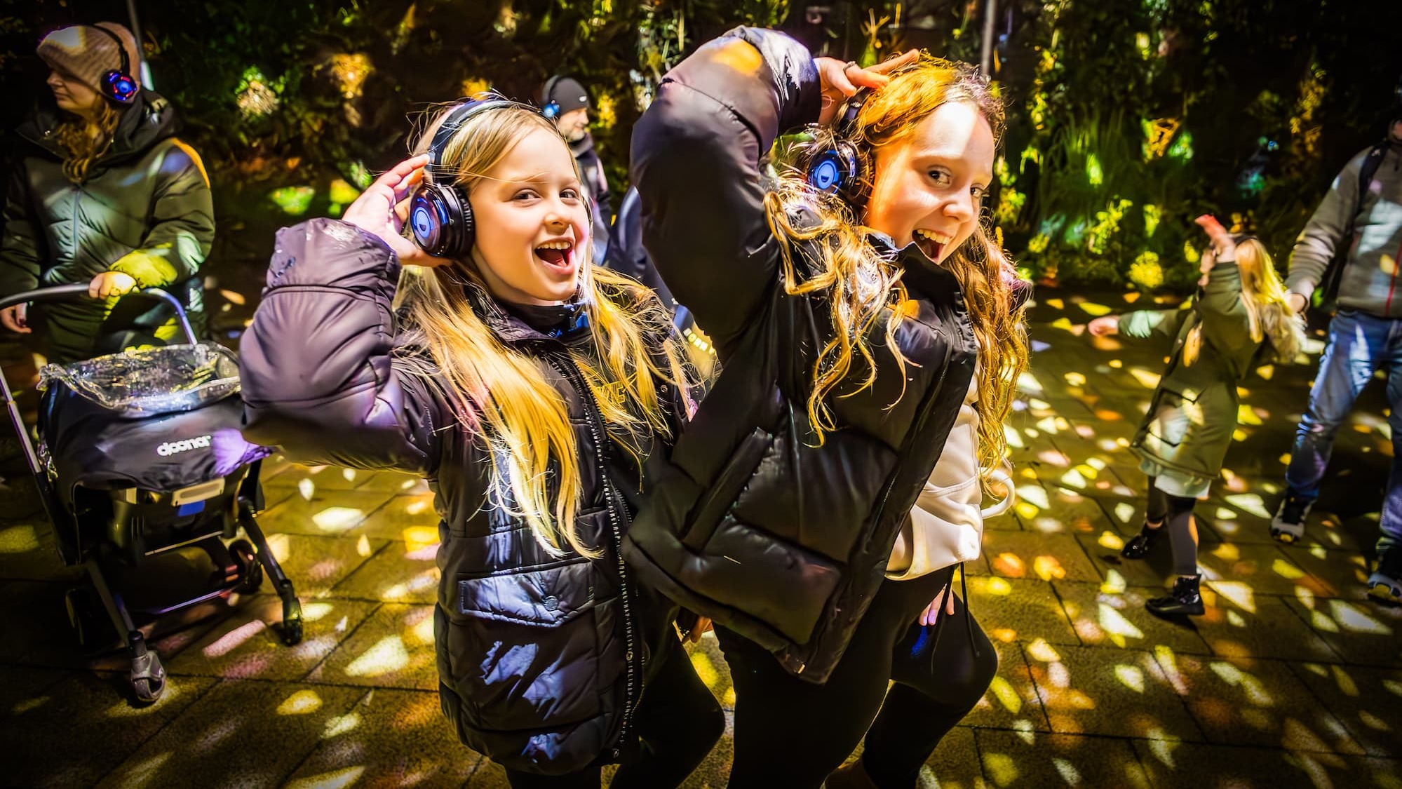 Two young children smiling on a dancefloor wearing headphones