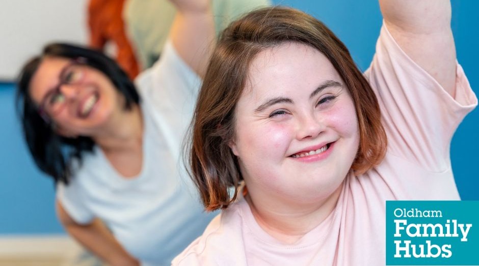 A young girl and an adult woman smiling as they have fun exercising together raising arms over their heads 
