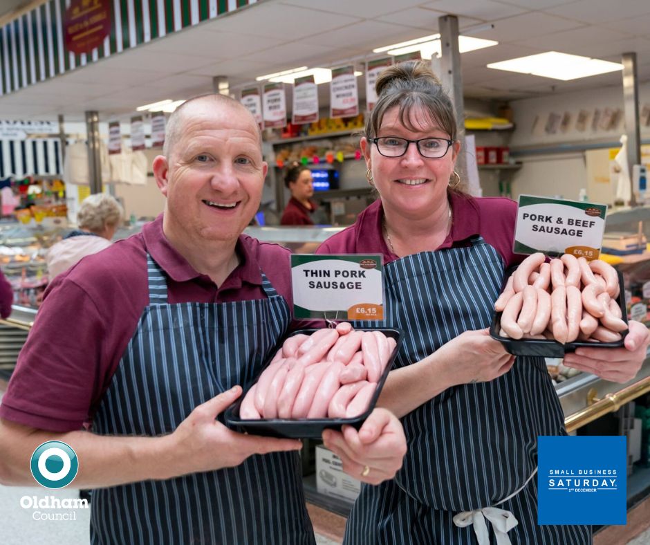 Two local butchers from Tommyfield Market holding sausages.