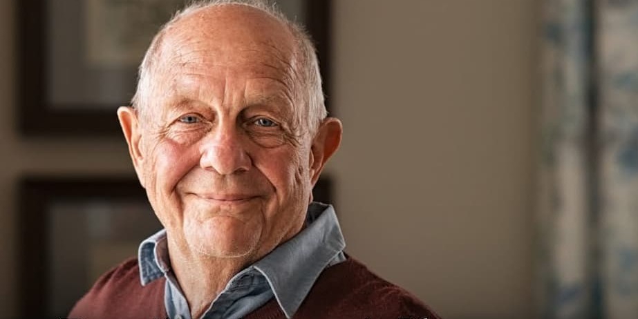 An elderly man smiling into the camera
