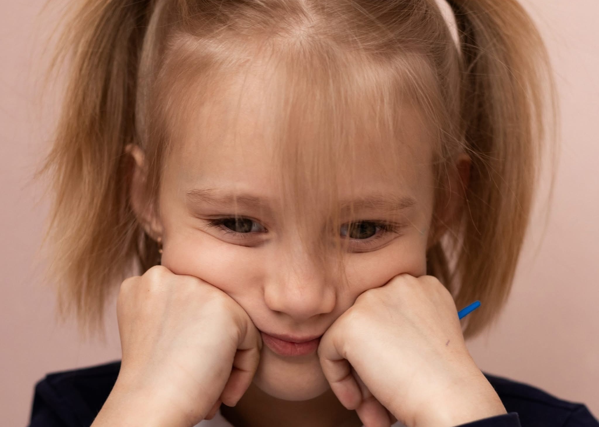 A sad looking little girl resting her head in her hands 
