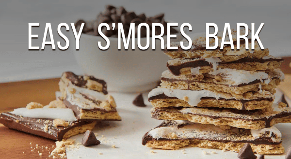 Stacked pieces of s'mores bark on a table with a bowl of chocolate morsels