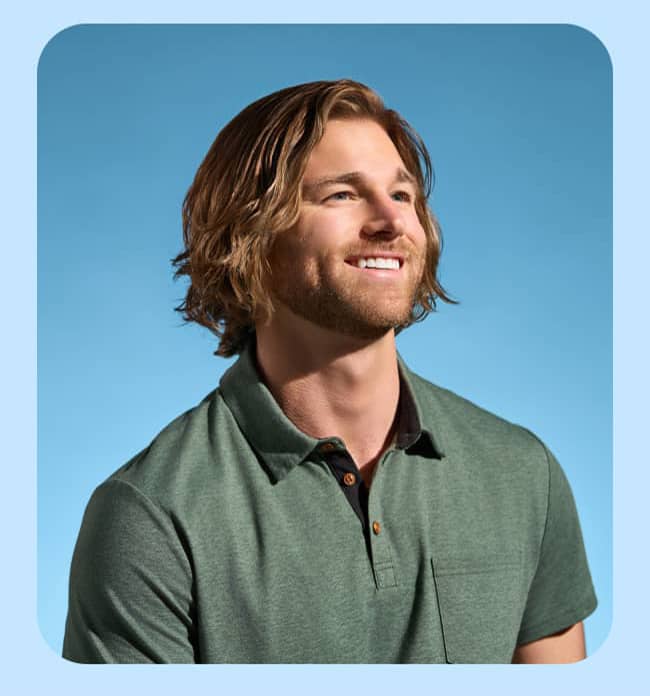 A blond man with a beard in a green shirt smiles toward the sun.