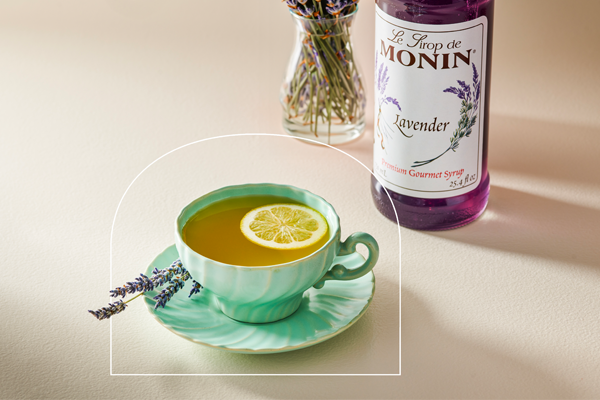 Saborizante de Lavanda Monin sobre una mesa junto a una bebida de té caliente.