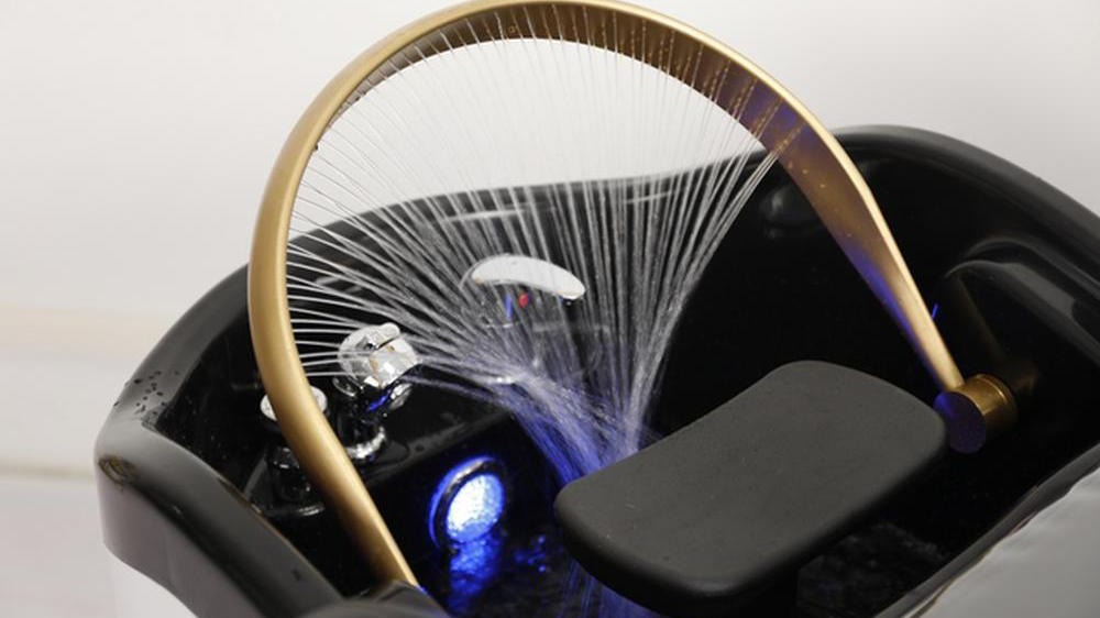 A closeup of a Japanese Head Spa water halo, with water spraying out of the halo into the shampoo bowl.
