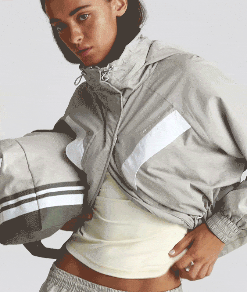 Video of a woman wearing a pale khaki spray jacket and spray pant.