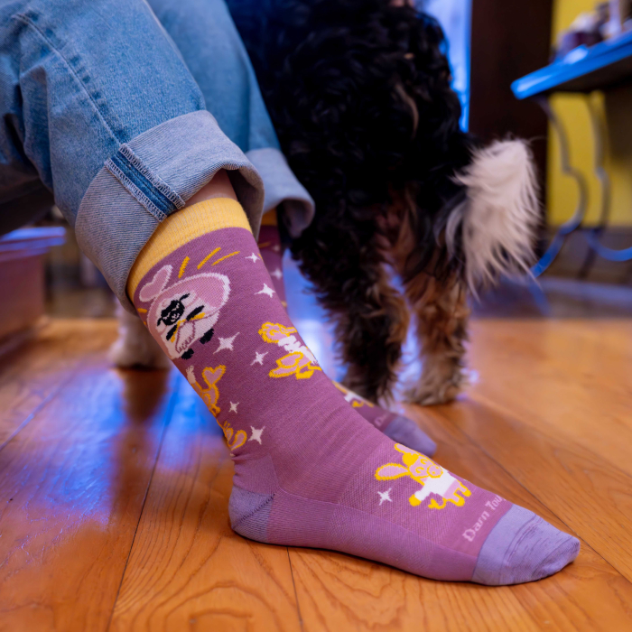 SHOP KNIT TO GIVE - photo of person wearing jeans and pink sock with lamb illustrations