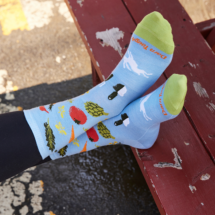Shop socks that give - feet kicked up on a picnic table wearing light blue socks with vegetables