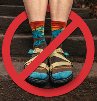 Read the blog - a hiker wearing sandals with Chasing Waterfalls socks with the no symbol