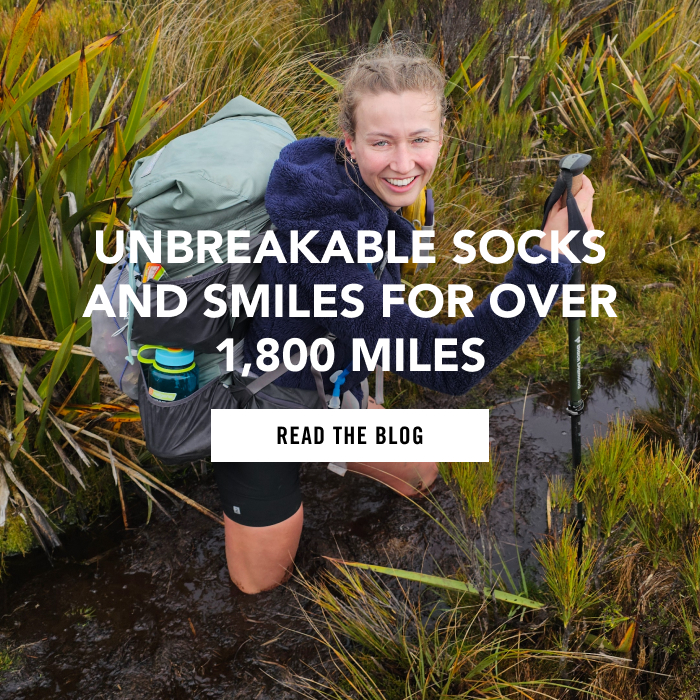 Read the Blog - a hiker smiles while thigh-deep in a muddy swamp during a 1800 mile hike