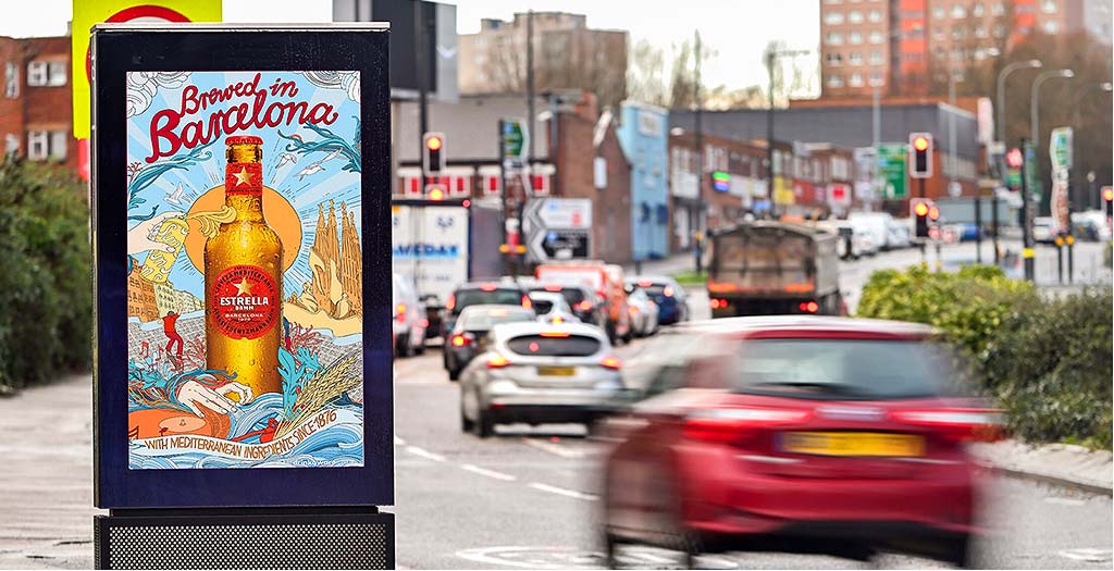A printed drinks advertisement on a standard roadside advertising panel beside moving traffic