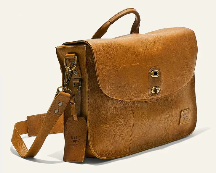 Tan leather messenger bag with shoulder strap, top handle, and brass hardware. Fearrington Village.