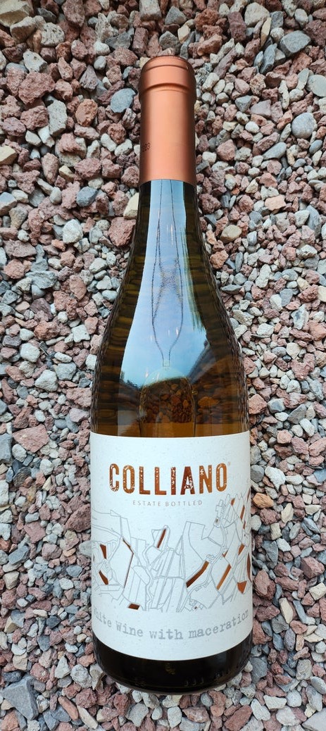Bottle of Colliano Skin Contact White Wine with a modern illustrated label and copper capsule, photographed against a textured gravel background.