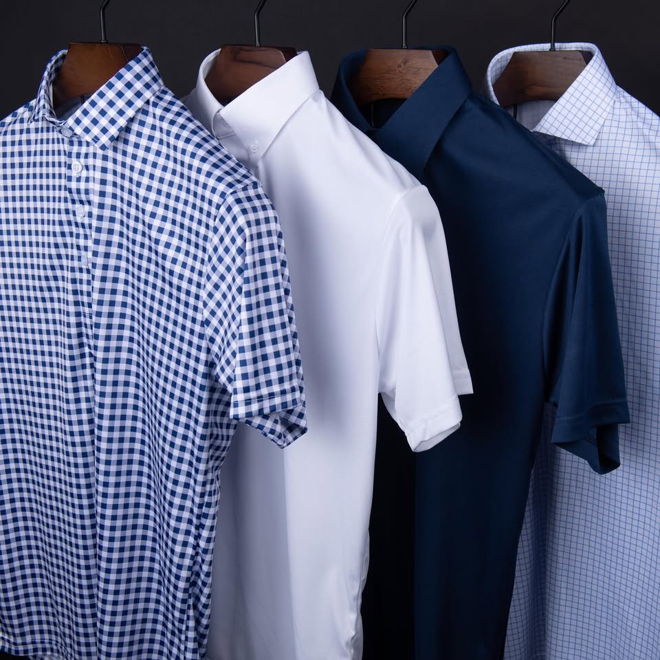 Four men’s short-sleeve shirts hanging on wooden hangers, including blue gingham, white, navy, and a light grid pattern.
