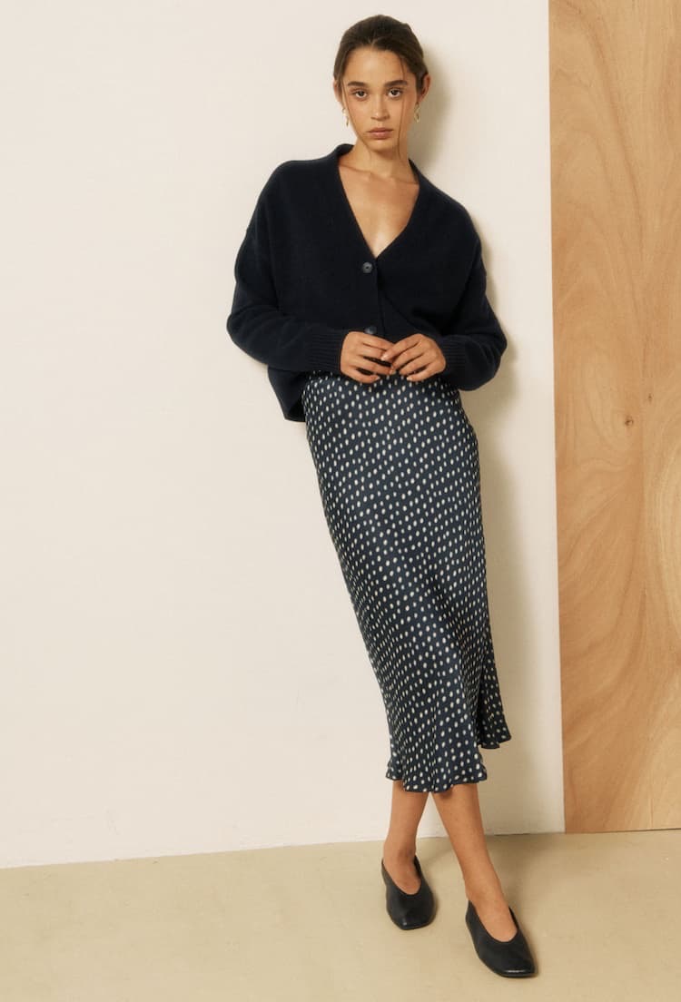 Woman wearing a navy cardigan with a navy patterned midi skirt and black flats. Fearrington Village.